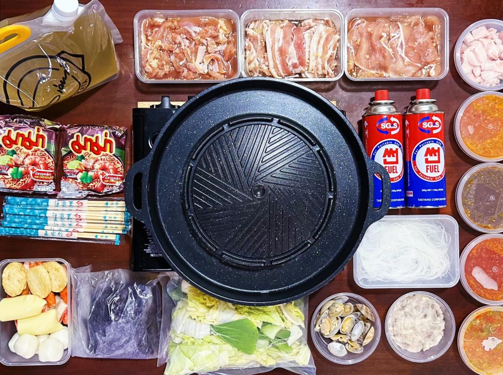 A table with a variety of Thai food mookata set items delivered for home self preparation